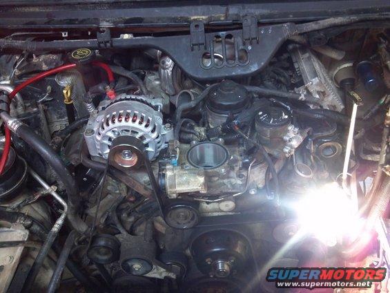 Engine bay showing alternator, belts, and various engine components