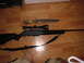 1993 Ford Bronco - A rifle and a hunting knife are laid out on a wooden floor, with a partial view of a person's legs and feet.