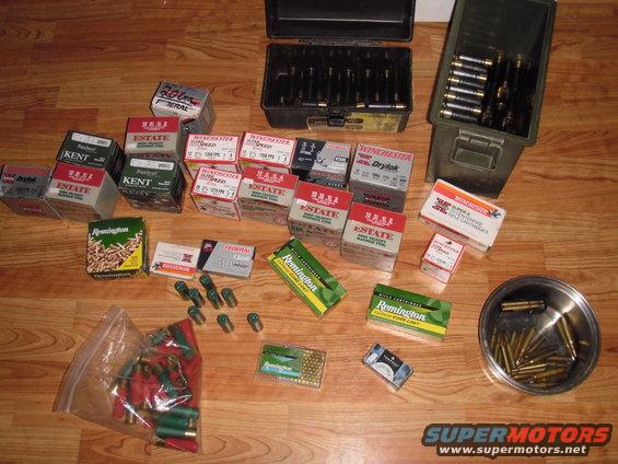 Various boxes of ammunition and ammo cans on a wooden floor
