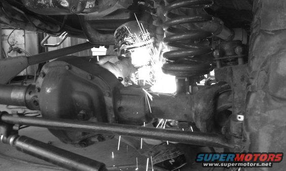 Welding sparks fly near the rear axle and coil spring of a vehicle