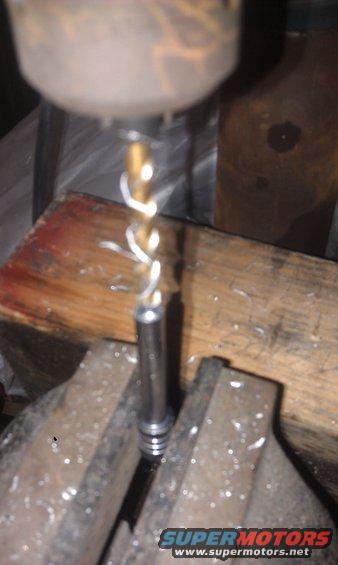 drill press bit working on metal part held in vise