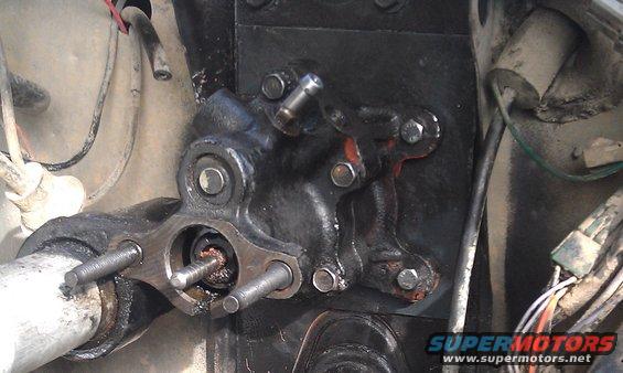 Close-up of a hydroboost brake booster assembly with bolts and hoses