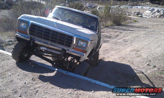White Ford F-Series truck with lifted suspension on a dirt road