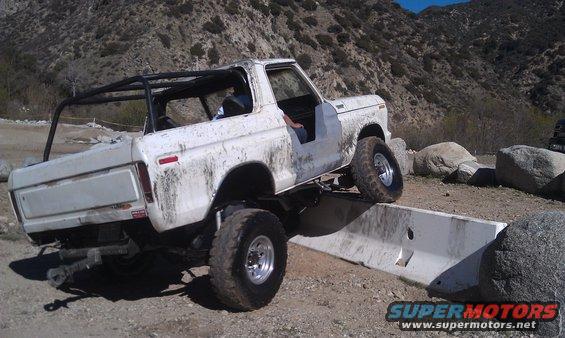 White 1978 Ford Bronco flexing over obstacle