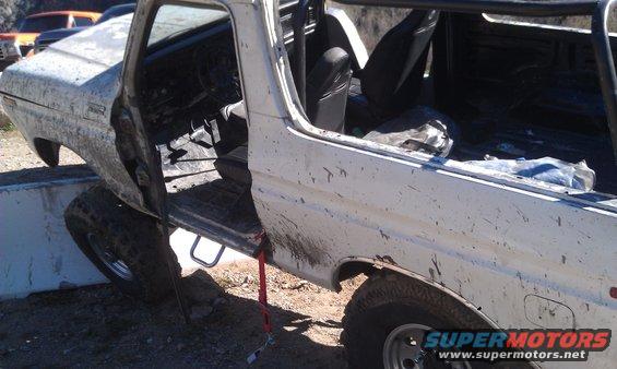 White SUV with open doors, tires on concrete barrier, mud splatters