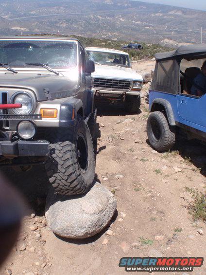 1978 Ford Bronco front view, parked behind a Jeep Wrangler with a blue Jeep CJ to the right