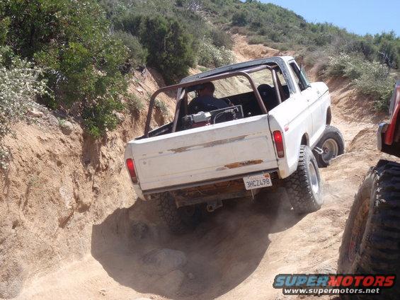 White SUV with roll cage going off-road. License plate reads 3HCZ498