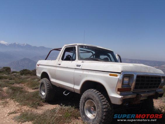 White 1978 Ford Bronco with roll cage parked on a hill