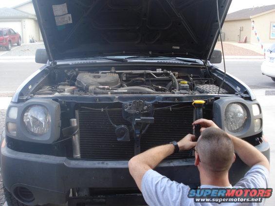2004 Nissan Xterra with hood open, man working on engine