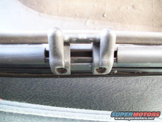 Close-up of a sunroof latch mechanism with two plastic clips and screws