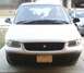 1997 Plymouth Voyager - A white minivan is parked in front of a garage. Another vehicle is parked to its right.