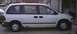 1997 Plymouth Voyager - Side profile of a white minivan with its sliding doors closed, parked in front of a building.