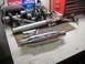 1978 Ford Bronco - An exhaust muffler and engine crankshaft are on a workbench with tools and fluids.