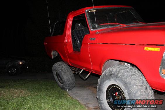Red lifted SUV with big tires, parked next to a dark SUV at night