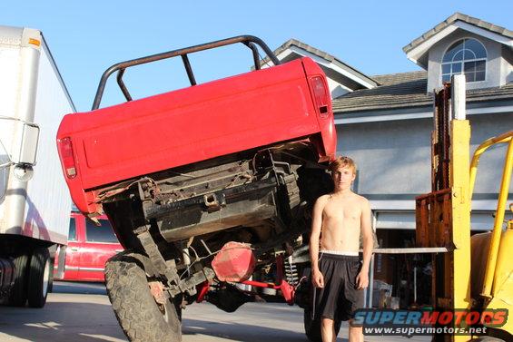 Red 1978 Ford Bronco lifted on a forklift, viewed from the rear