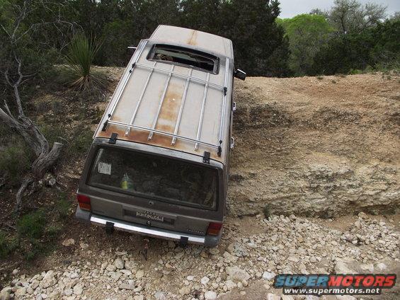 Brown SUV with roof rack tilted on rocky terrain
