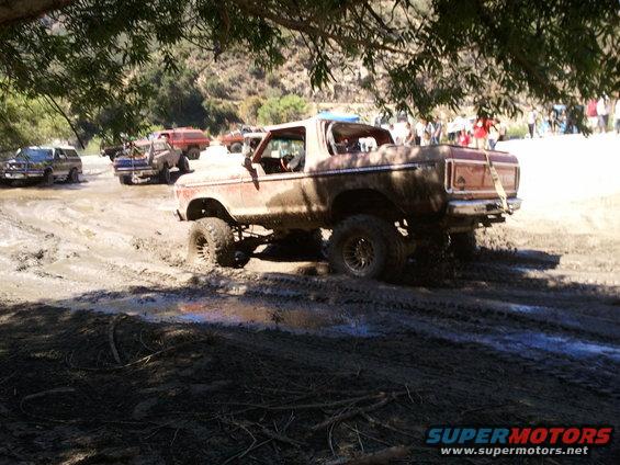 Muddy 1978 Ford Bronco and other off-road vehicles in a muddy area