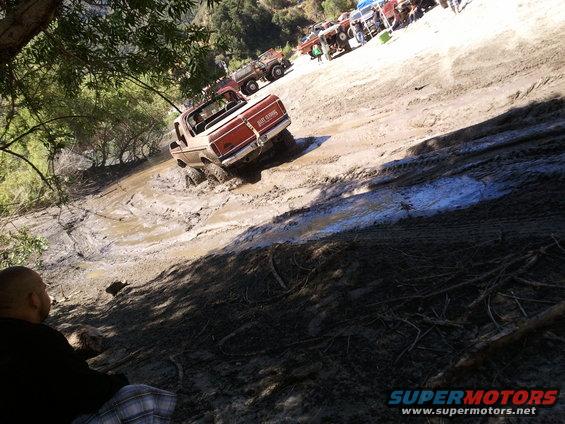 1978 Ford Bronco navigating a muddy hill with other off-road vehicles in the background
