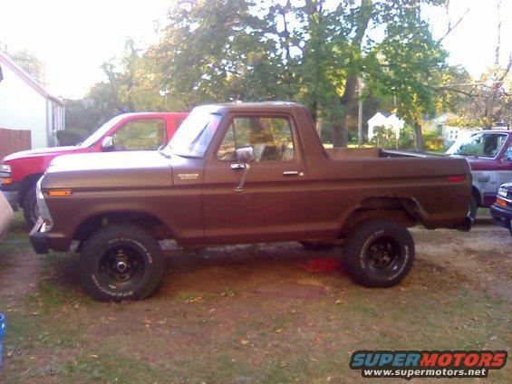 1979 Ford Bronco parked next to a red pickup truck