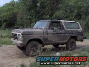 Old Ford Bronco parked on dirt road with trees in background