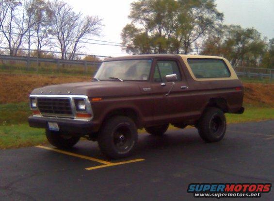 Brown two-door Ford Bronco with a tan top, parked in a lot. Front 3/4 view