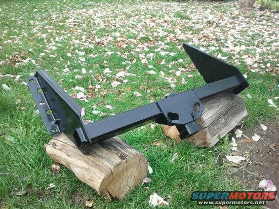 black trailer hitch resting on logs outdoors