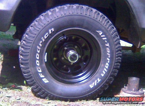 BFGoodrich All-Terrain T/A tire on a black rim, with a spare hub assembly nearby
