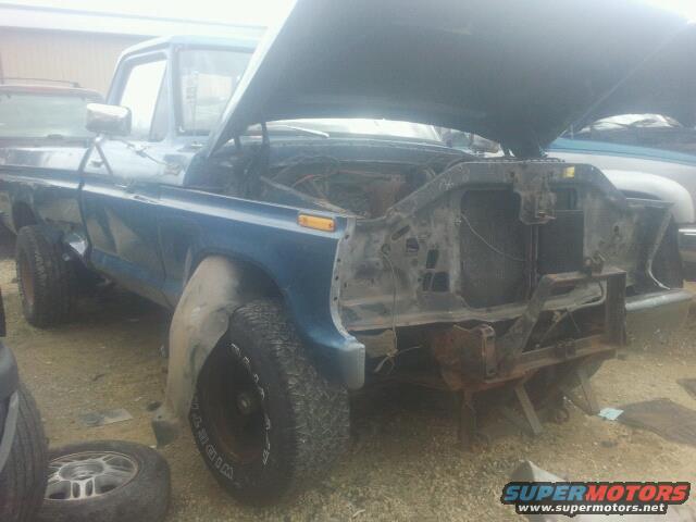 blue pickup truck with hood open, front end dismantled, parked outside
