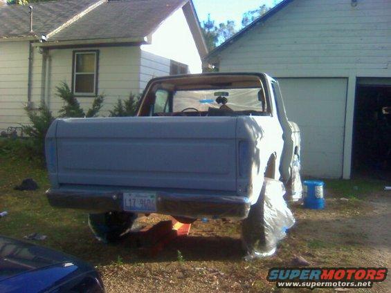 Rear view of a 1979 Ford Bronco, gray, with plastic wrap on wheels