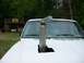1985 Ford Bronco - A custom exhaust stack protrudes through the hood of a white truck, with a rustic building in the background.