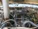1985 Ford Bronco - The engine bay shows an aftermarket air intake and significant rust on various parts.