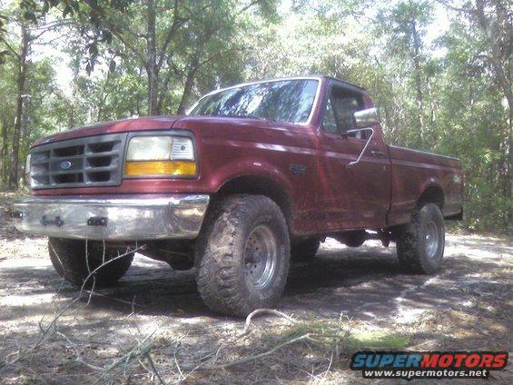 Maroon Ford F-150 pickup truck parked on a dirt path in a wooded area
