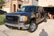 2007 GMC Sierra 1500 - A brown 2007 GMC Sierra 1500 pickup truck is parked in front of a brick house and garage.