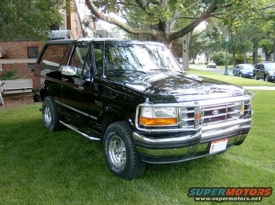 Black 1995 Ford Bronco parked on a lawn in front of a brick building