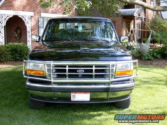 Black Ford Bronco with chrome grille guard parked on grass in front of a brick house