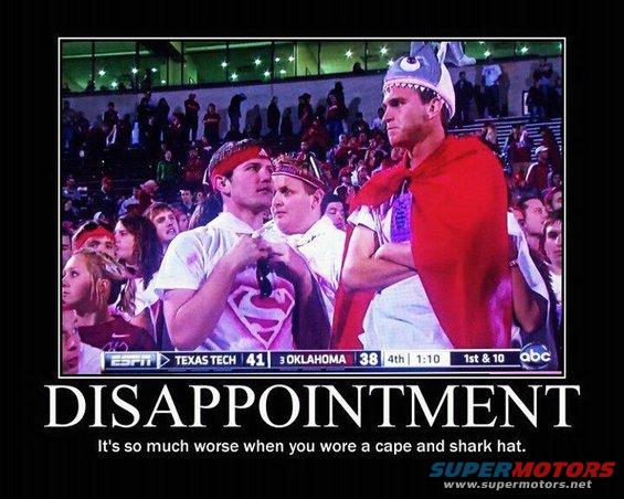 Crowd at a game with a man in a red cape and shark hat