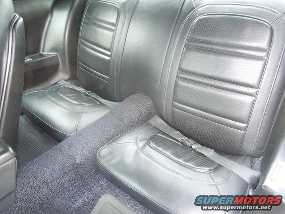 Black vinyl rear car seats with lap belts and dark grey carpet