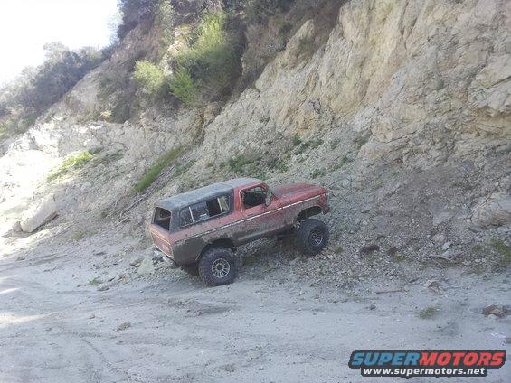 Red 1978 Ford Bronco on a dirt slope, with a black hardtop and large off-road tires