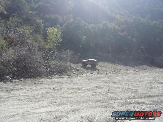 1978 Ford Bronco parked on a dirt slope with trees in the background