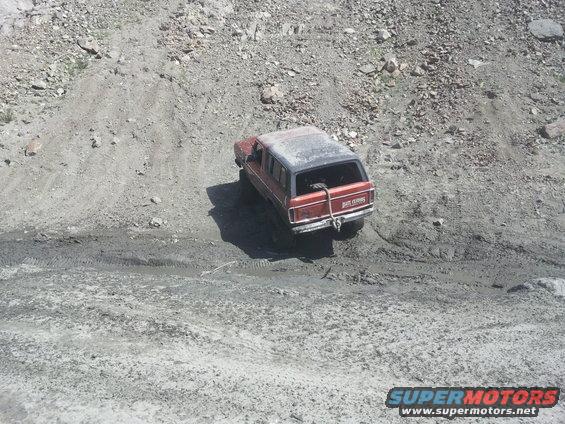 1978 Ford Bronco, red with black top, on muddy incline