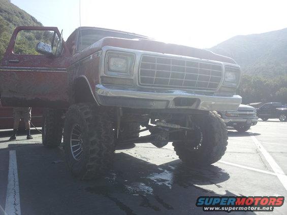 Red lifted 6x6 truck with large tires and a prominent grille
