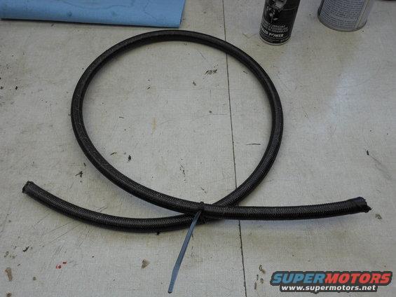 Black braided hose coiled on a workbench with a zip tie