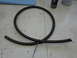 2005 Honda CR125R - A black braided hose is coiled on a workbench, secured with a zip tie, with cans in the background.