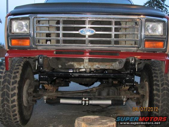 Front grille and suspension of a red Ford truck with a chrome grille and large tires