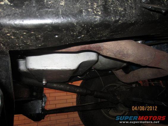 Underside of a vehicle showing the transmission pan and exhaust pipe