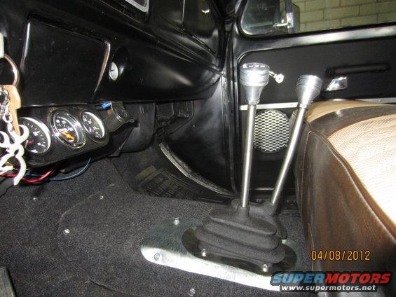 Interior shot of a vehicle showing two gear shifters, gauges on the dash, and part of a seat