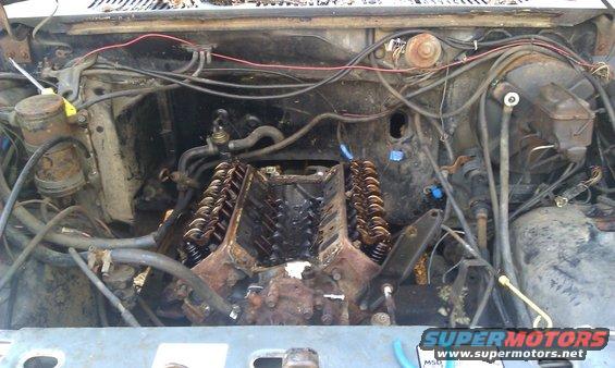 Engine bay with V8 engine exposed, wires and hoses visible