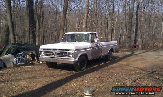 White 1973 Ford F-100 pickup truck parked outdoors, front 3/4 view, with a wooded background