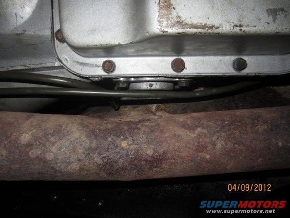 Close-up of a transmission pan and rusted exhaust pipe