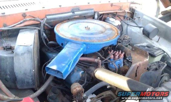 Engine bay of a 1973 Ford F-100, showing the blue air cleaner, distributor, and orange fender